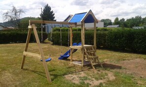 Relax in a serene backyard with a charming swing set and slide.