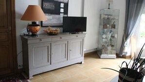 Olohuoneessa on televisiotaulutaso, lamppu, kehystetty taideteos ja lasivitriini.