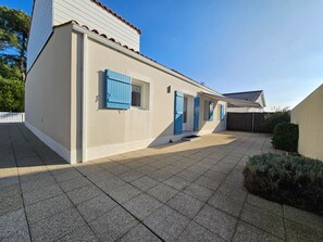 A building with a tiled patio, blue shutters, and a white exterior.