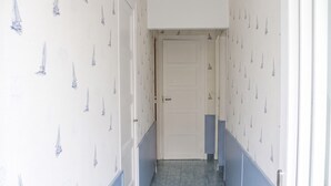 Ein schmaler Korridor mit gemustertem Wandpapier und einer Tür am Ende.