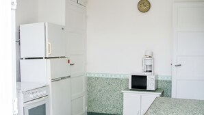 Eine kleine Küche mit Kühlschrank, Backofen, Mikrowelle und Kaffeemaschine.