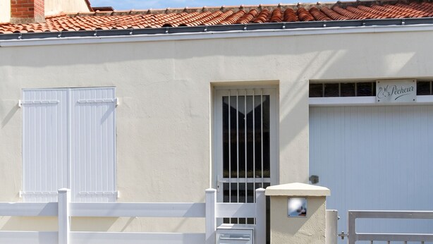 Ein Gebäude mit weißer Fassade, einem Metallgitter und einem Fenster mit Metallstreben.