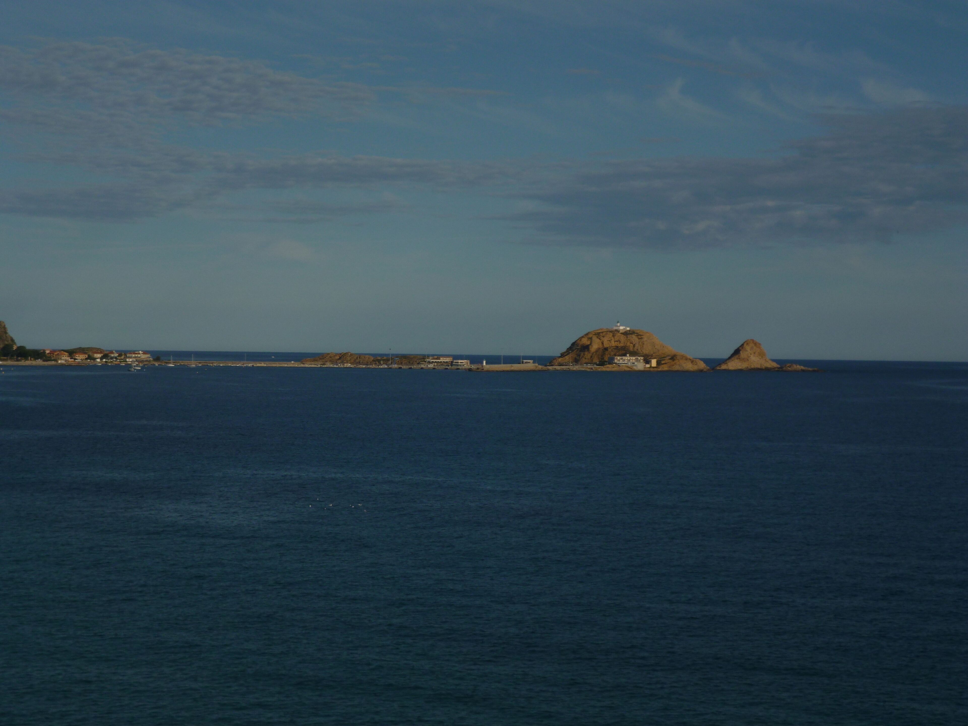 A coastal landscape with a prominent rocky outcrop and a lighthouse.