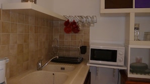 A kitchen with a sink, a microwave, and a dish rack. - studio in quiet and sunny property near the sea. (monticello)
