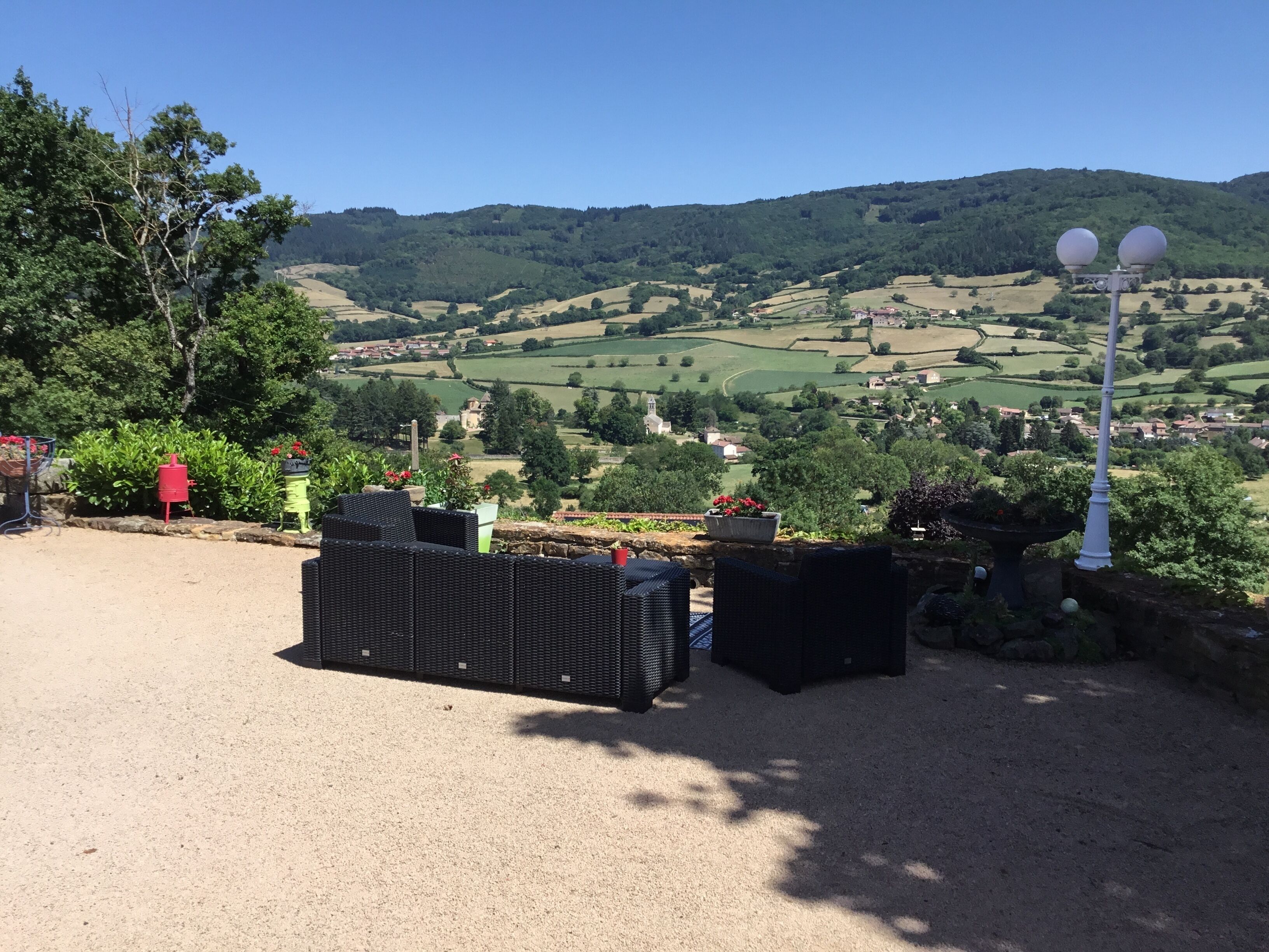 Une vue sur un paysage rural, avec des collines ondoyantes, un ciel dégagé et un village situé au loin.