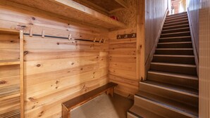 Ein Holzinnenraum mit Treppe, Holzbanken und einem an der Wand befestigten Ablagefach.