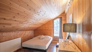 Ein Zimmer mit Holzwandverkleidung, einem Bett, einem Schreibtisch und einer Lampe.