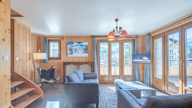 Ein Holzinnenraum mit einer Couch, einem Sessel, einem Fernseher und einem Bild an der Wand.