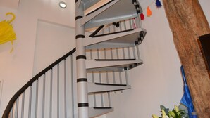 Una escalera de caracol con barandilla de metal y pasamanos de madera, que conduce a un piso superior.