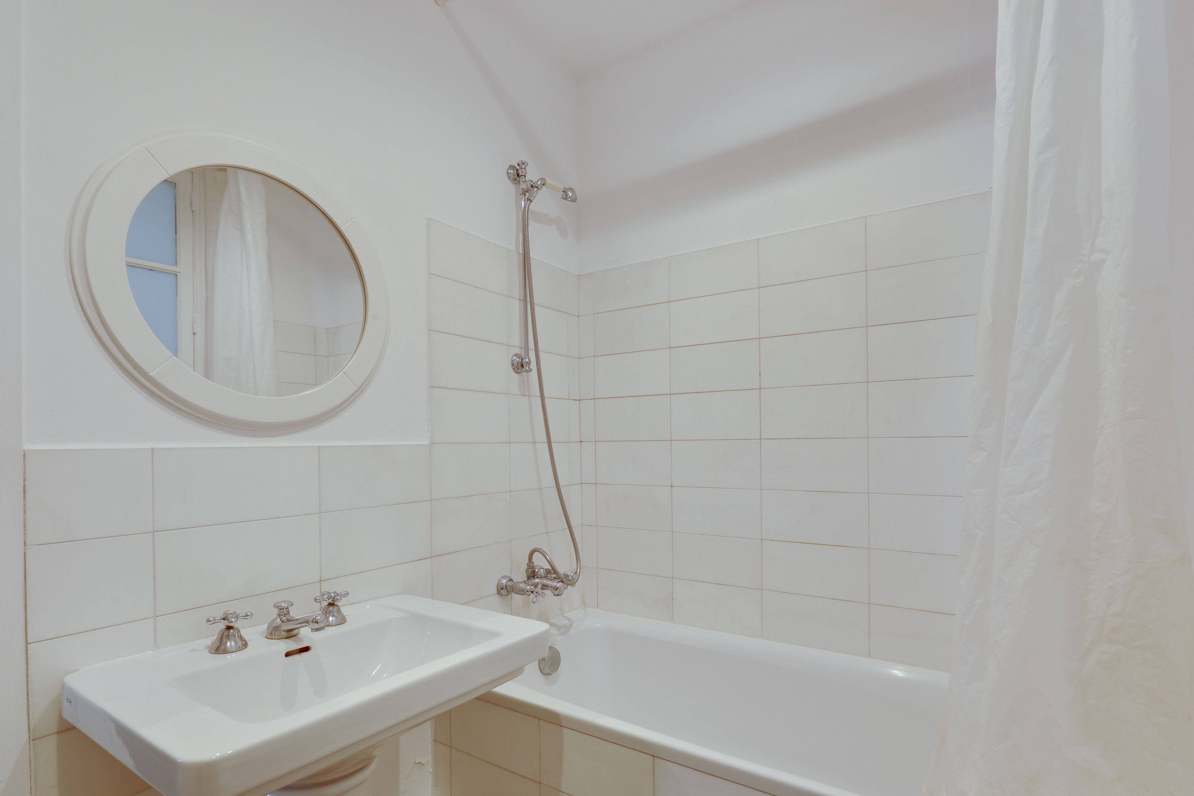 Une salle de bain avec un lavabo blanc, une baignoire et une douche avec un rideau.
