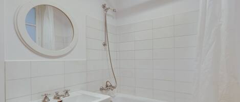 Une salle de bain avec un lavabo blanc, une baignoire et une douche avec un rideau.