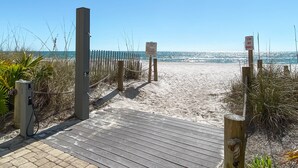 A wooden boardwalk leading to a sandy beach with a clear blue sky. - Come Enjoy this luxury condo right on the beach of Gulf Shores! (Orange Beach)