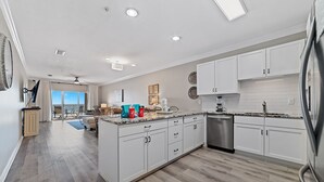 A modern kitchen with white cabinets, a granite countertop, and a stainless steel dishwasher. - Come Enjoy this luxury condo right on the beach of Gulf Shores! (Orange Beach)