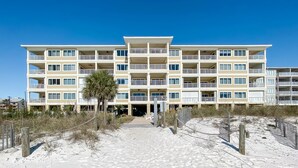 A multi-story hotel with balconies, a sandy beach in front, and a clear blue sky. - Come Enjoy this luxury condo right on the beach of Gulf Shores! (Orange Beach)