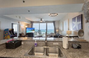 Une chambre d’hôtel équipée d’un coin cuisine, d’une télévision, d’un balcon avec vue sur l’océan et d’un ventilateur de plafond.