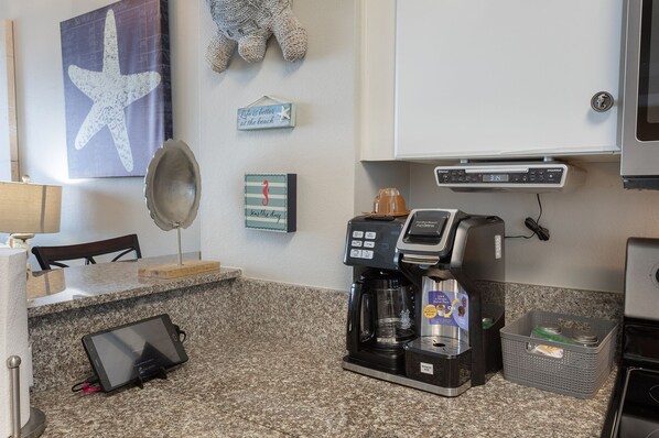 A kitchen area with a coffee maker, a tablet, and a refrigerator.