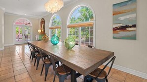 Un comedor con una larga mesa de madera, sillas y jarrones de vidrio decorativos.