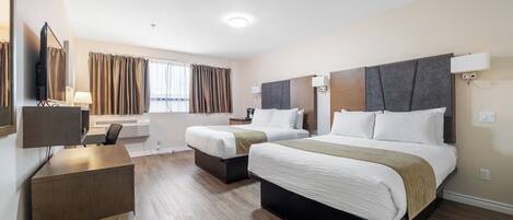 Ein Hotelzimmer mit zwei Betten, einem Schreibtisch, einem Sessel, einem Fernseher und einem Fenster mit Vorhängen.