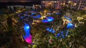 Un resort con varias piscinas, palmeras y vista al océano.