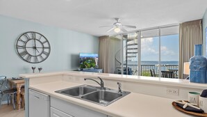 Una cocina moderna con un ventanal grande, un ventilador de techo y vistas al mar.