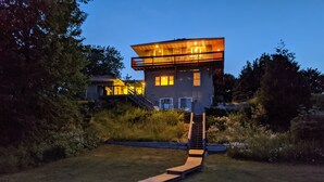 A modern two-story house with a wooden deck leading to the front door.