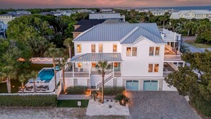 A two-story house with a pool, multiple decks, and a view of the ocean.