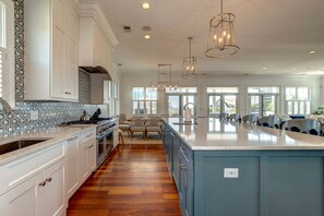 A spacious kitchen with a large island, white cabinetry, and a patterned backsplash.