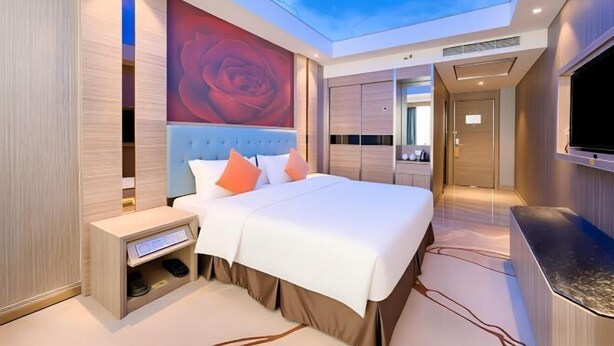 A modern hotel room with a large bed, a TV, a wardrobe, and a skylight. - Oriental Paris Business Hotel (Shishi)