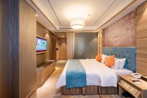 A hotel room with a large bed, a television on the wall, and a wooden panel design. - Oriental Paris Business Hotel (Shishi)