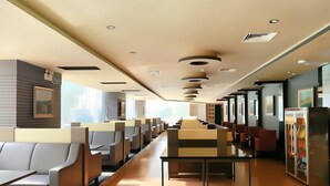 A modern hotel lobby with rows of seating, a reception desk, and a large window providing natural light. - Oriental Paris Business Hotel (Shishi)