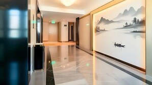 A modern hotel lobby with a polished marble floor, a large wall mural of a serene landscape, and a sleek reception desk. - Oriental Paris Business Hotel (Shishi)
