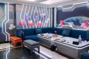 A modern room with a blue sofa, a coffee table, and a wall with geometric patterns and balloons. - Oriental Paris Business Hotel (Shishi)