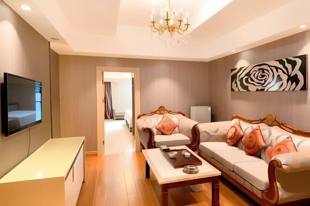 A modern living room with a flat-screen TV, a wooden coffee table, and a sofa with patterned cushions.