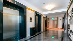 A modern hotel lobby with a polished marble floor, a reception desk, and a large wall-mounted artwork. - Oriental Paris Business Hotel (Shishi)