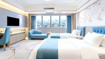 Quarto de hotel com duas camas, uma escrivaninha, uma cadeira, uma televisão e uma janela grande com vista para a cidade.