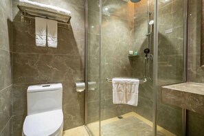 A bathroom with a glass-enclosed shower, a toilet, and a marble-tiled wall. - Oriental Paris Business Hotel (Shishi)
