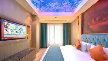 Ein Hotelzimmer mit einem großen Bett, einem flachbildfernseher an der Wand und einer Decke mit floralem Muster.