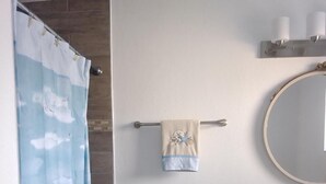 A bathroom with a toilet, a towel rack with a towel, a shower curtain, a sink with a marble countertop, and a mirror. - WATERFRONT COTTAGE w/ACCESS TO WEEKI WACHEE RIVER & GULF FRESHLY REMODELED! (Weeki Wachee)