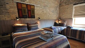 Una habitación de hotel con dos camas, un muro de ladrillo y una ventana.