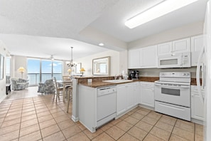 A modern kitchen with white cabinets, a granite countertop, and stainless steel appliances.