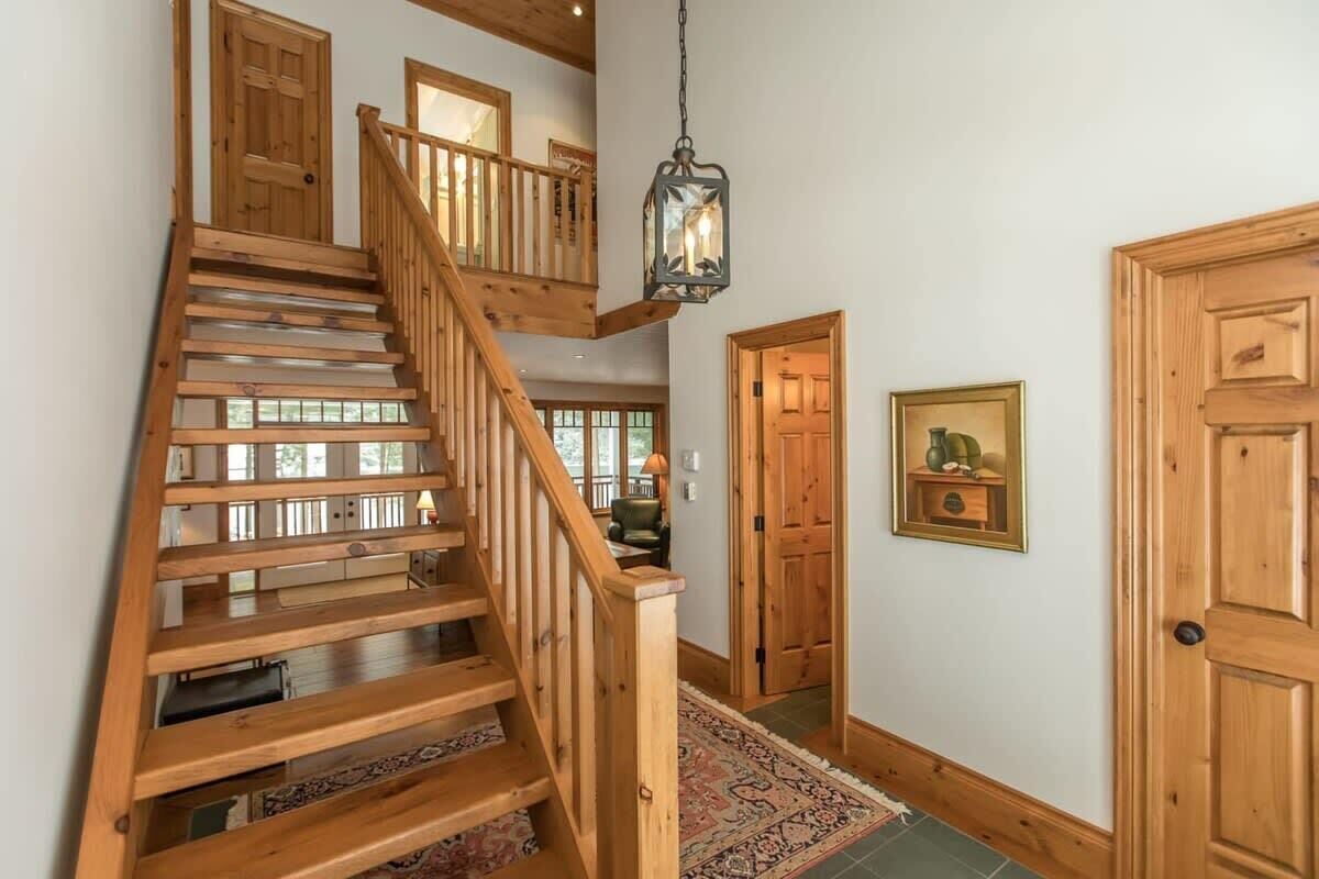 Un escalier en bois avec une rampe, une lanterne suspendue et un tapis à motifs.
