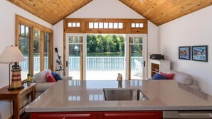 Eine Küche mit Kochinsel, Holzboden und großen Fenstern mit Blick auf eine Terrasse.