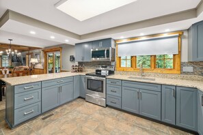 Enjoy cooking in this well-equipped kitchen with ample workspace and storage, featuring a range hood and oven, and a large window with views of the surrounding landscape.