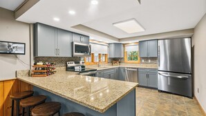 A modern kitchen with granite countertops, stainless steel appliances, and a central island with bar stools.