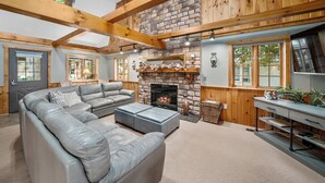 A cozy living room with a stone fireplace, leather sofa, and wooden beams.