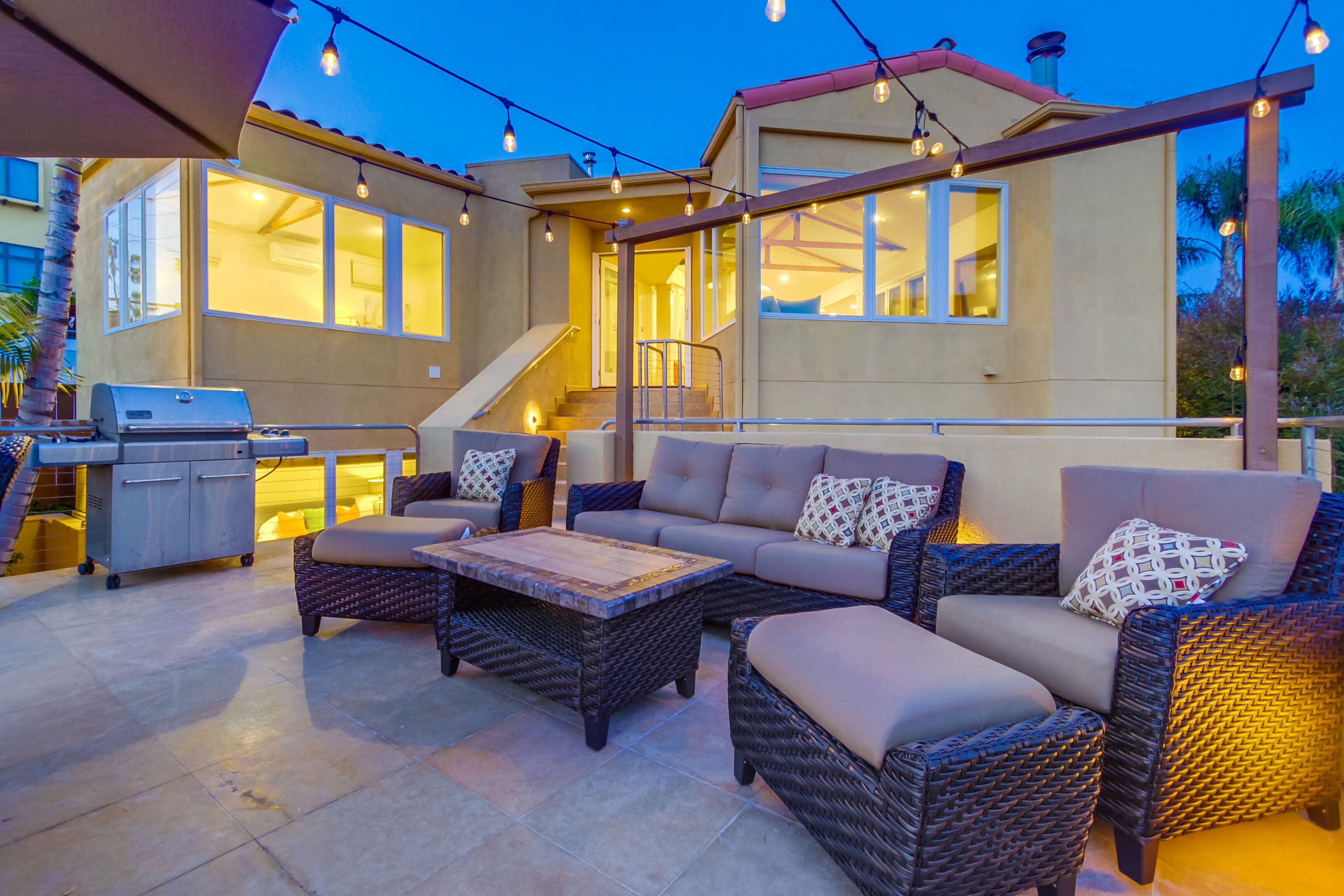 An outdoor patio area with wicker furniture, a grill, and string lights.