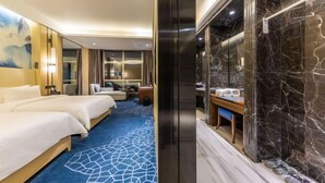 A hotel room with a large bed, a desk with a chair, a bathroom with a marble wall, and a blue carpet with a geometric pattern. - Longtan Hotel (Wuxue)