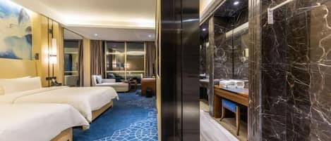 Une chambre d’hôtel avec un grand lit, un bureau avec une chaise, une salle de bain avec un mur en marbre et une moquette bleue à motifs géométriques.