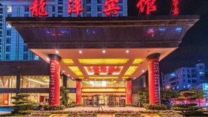 A hotel entrance with a prominent red sign, a covered entrance area, and a well-maintained garden in front. - Longtan Hotel (Wuxue)