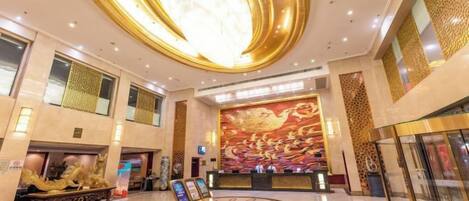 A spacious lobby with a large circular ceiling feature, a reception desk, and a decorative wall mural.
